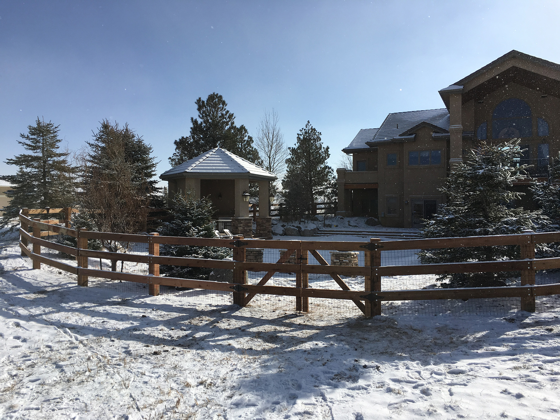 Custom brown treated ranch rail fence in the snow