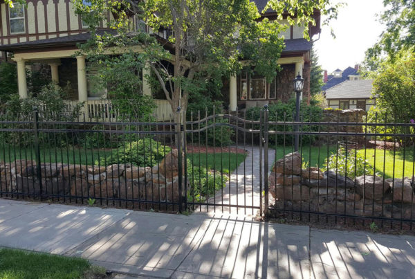 Beautiful backyard surrounded by custom black ornamental fence with an arched gate